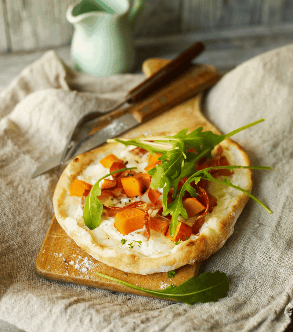 Mini pizza with squash, bacon and arugula