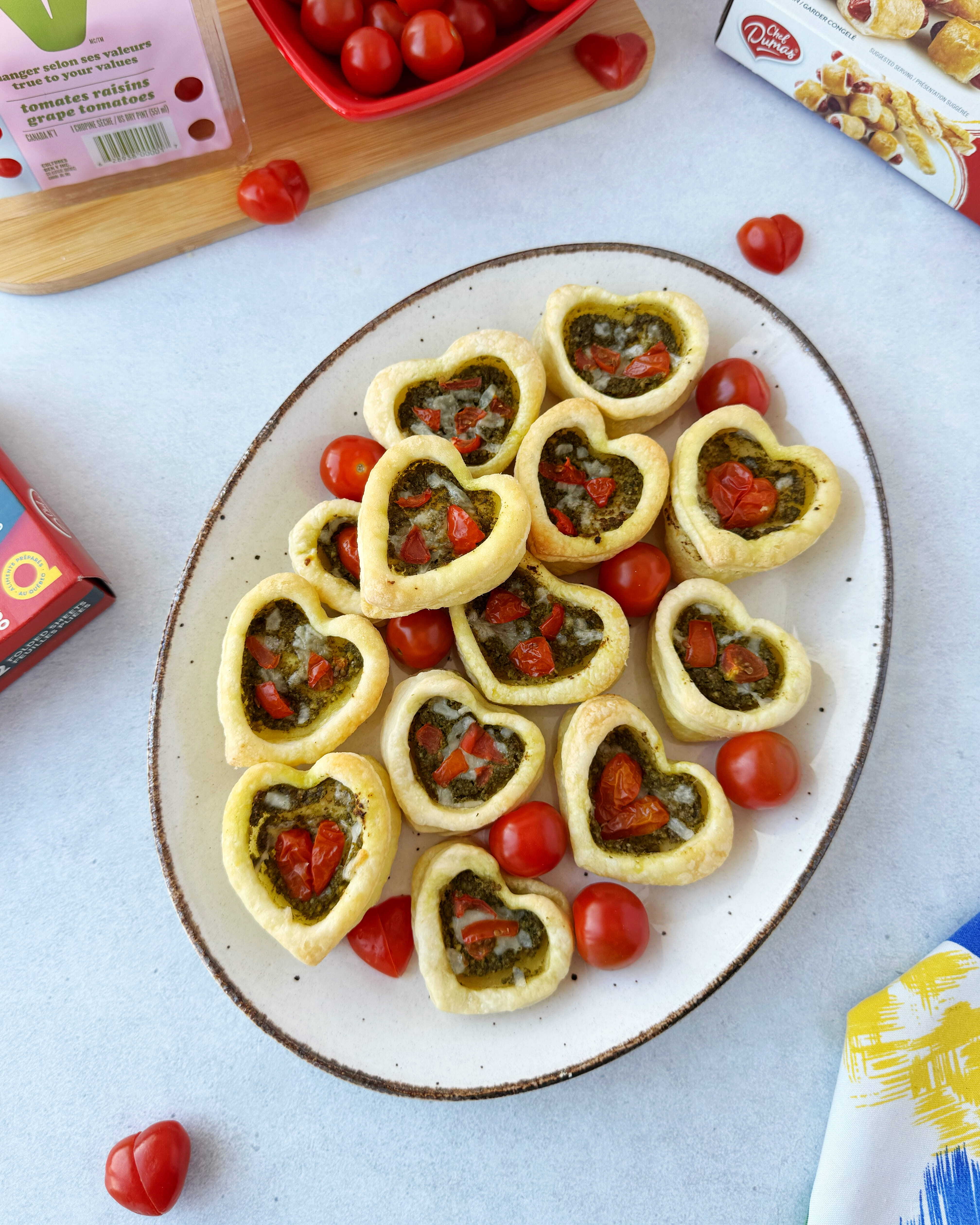 Heart-shaped puff pastries with pesto, cheese and cherry tomatoes